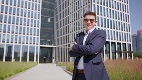 a successful entrepreneur in sunglasses smiles at the camera in a business district