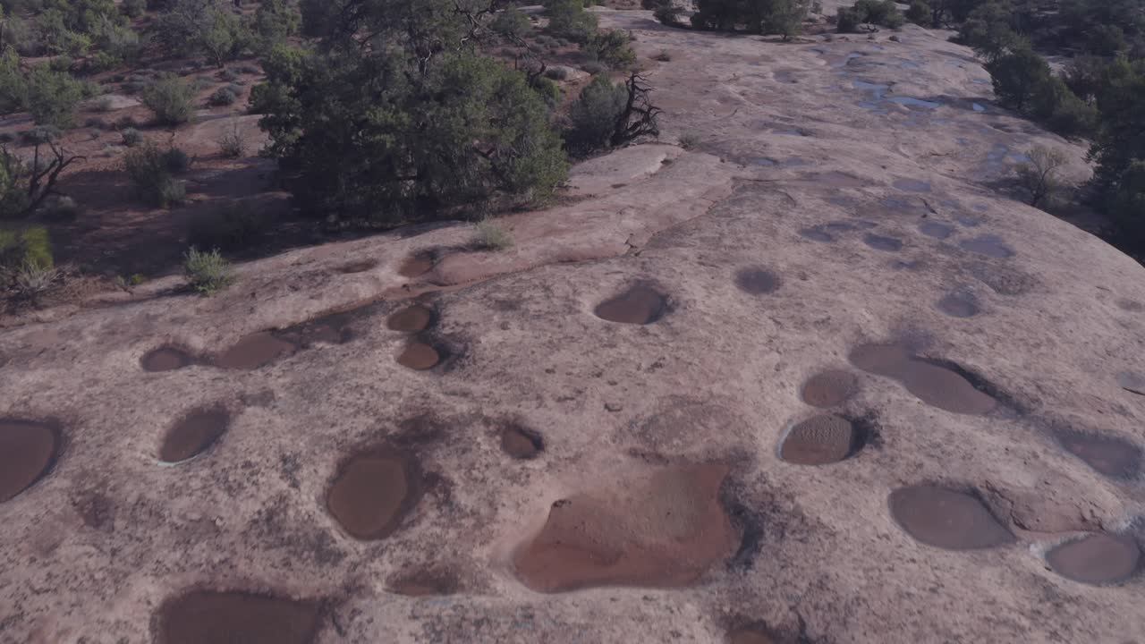 escena aérea sobre charcos de agua de lluvia en la roca resbaladiza en el desierto de moab - utah