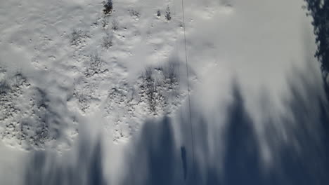 A-person-flies-down-a-zipline-over-a-frozen-lake-in-the-winter