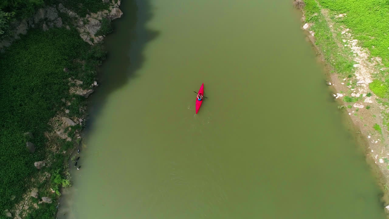 Lone Kayak paddles down river in Kosovo, Aerial rise shot