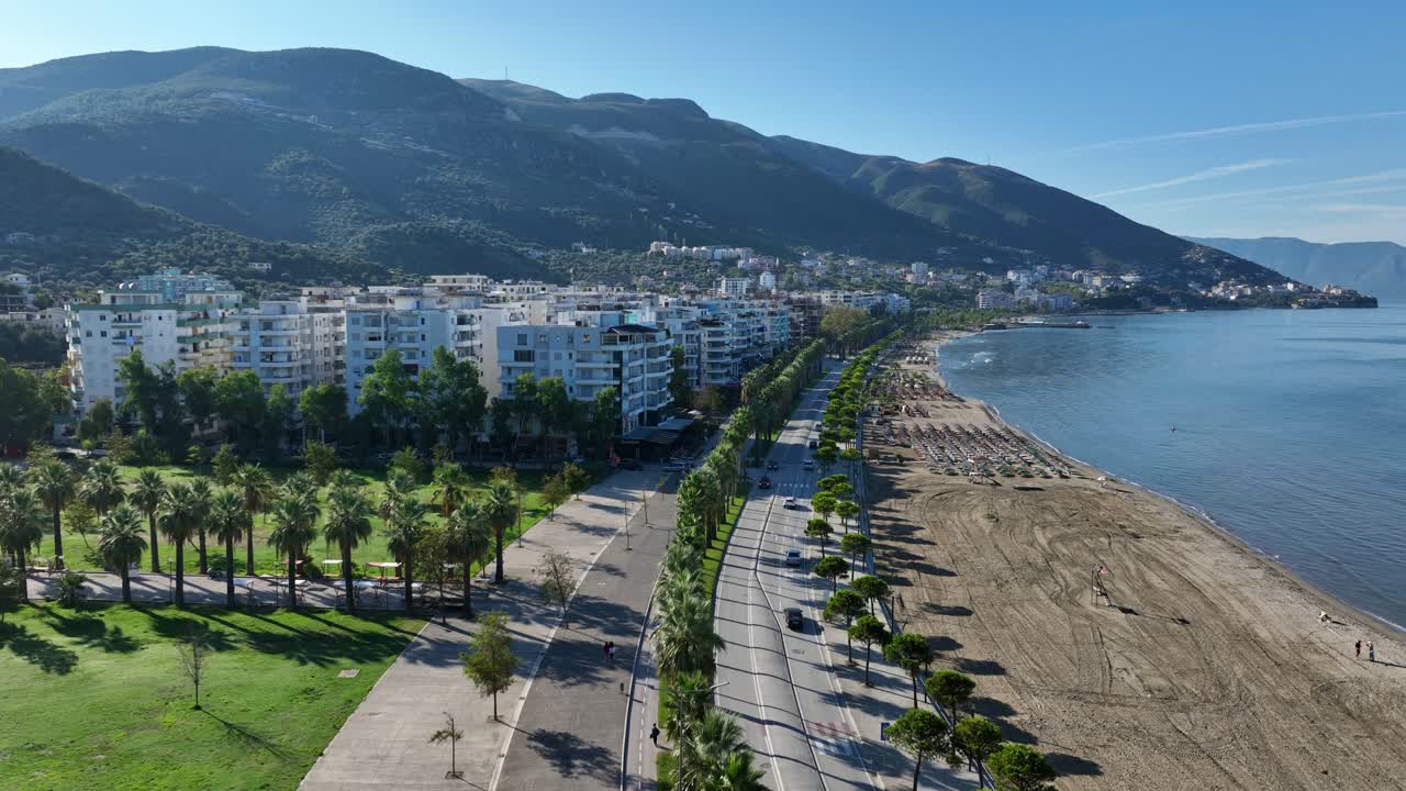 Beach and green mountains by city of Vlore in Albania, forward aerial