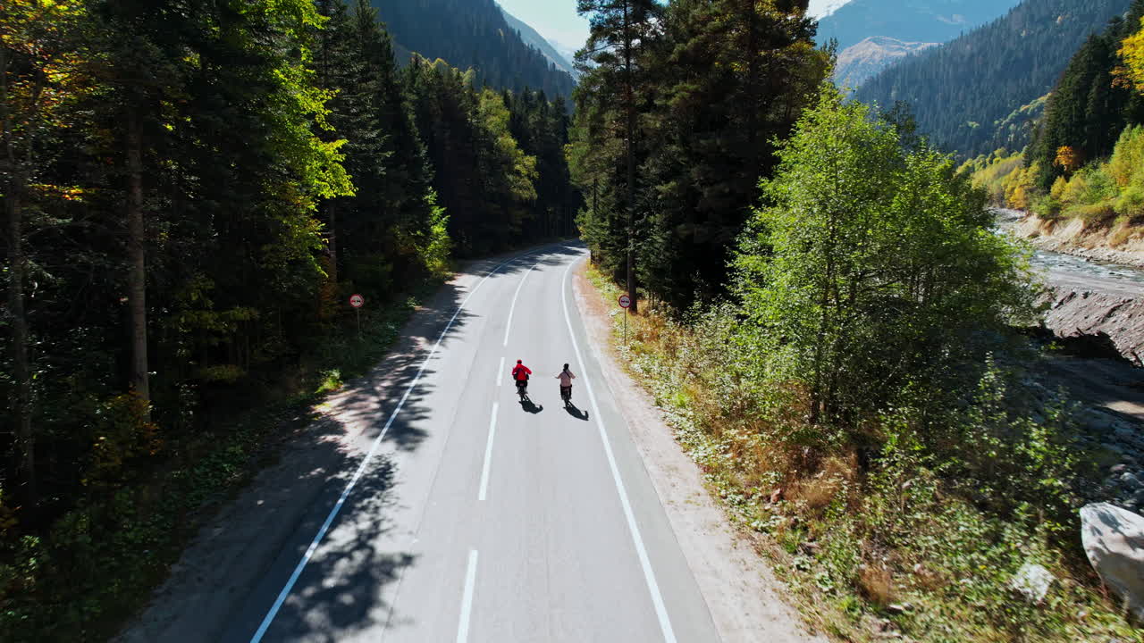 Cyclists on a Mountain Road in Autumn Forest