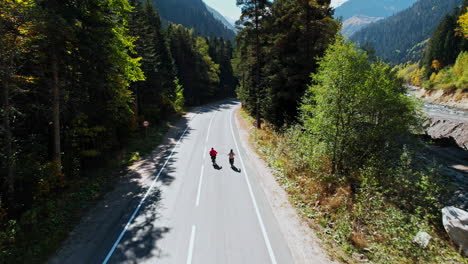 cyclists on a mountain road in autumn forest