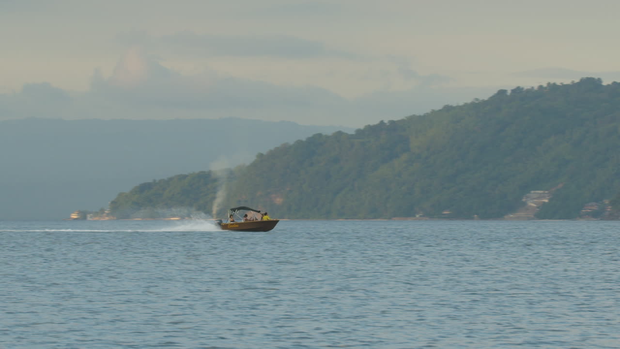 tiro largo de una pequeña lancha rápida entrando en una cala en una isla remota