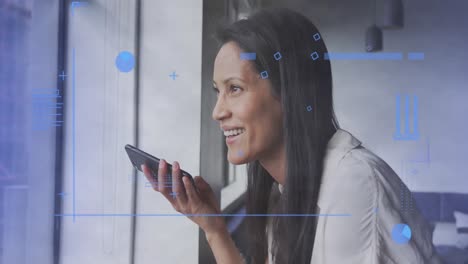 animación del procesamiento de datos financieros sobre una mujer de negocios biracial usando un teléfono inteligente en la oficina.