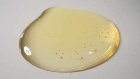 Drops-of-fresh-jojoba-oil-falling-down-spreading-on-surface