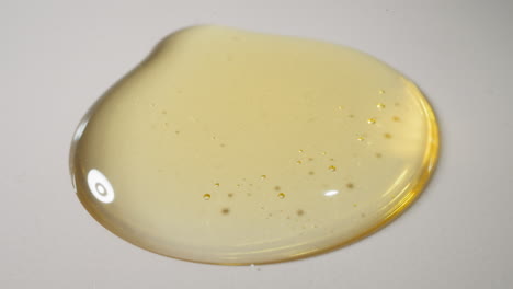 drops of fresh jojoba oil falling down spreading on surface