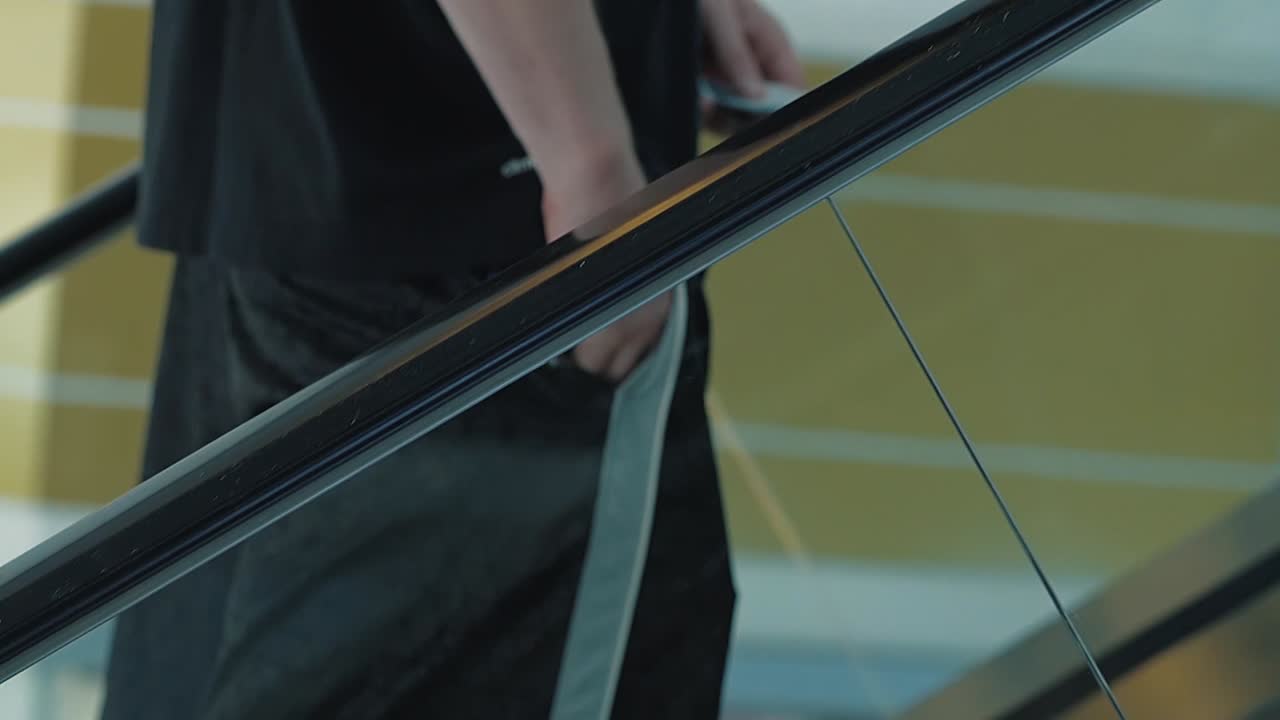 un joven sube por la escalera mecánica pone algo en su bolsillo