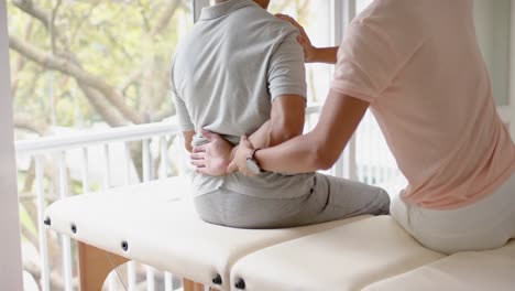 diverse male physiotherapist advising and senior male patient exercising, in slow motion