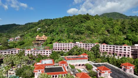aerial footage of a resort nestled in lush green hills under a bright blue sky in phuket, thailand
