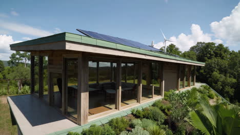 modern house with green roof, solar panels, and wind turbine