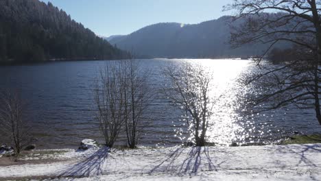 wide shot of the snowy longemer lake and surrounding mountain forest in vosges, france