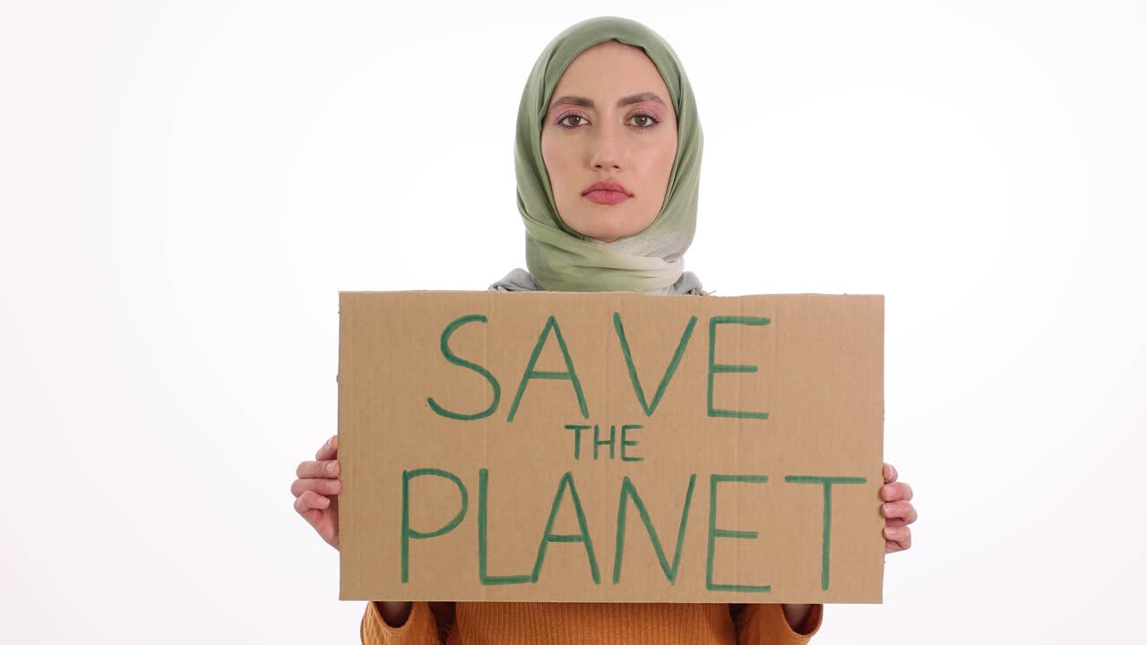 Woman in hijab holding 'Save the Planet' sign