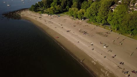 Gente-Tomando-El-Sol-Y-Disfrutando-De-La-Playa-Kitsilano-Reabierta-Con-El-Horizonte-Del-Centro-Y-La-Playa-De-English-Bay-En-Vancouver,-Columbia-Británica,-Canadá