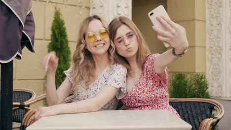 two friends taking a selfie at an outdoor cafe