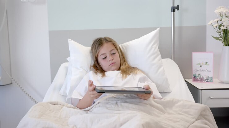 Ragazza paziente caucasica stanca sdraiata in un letto d'ospedale che usa un tablet, al rallentatore