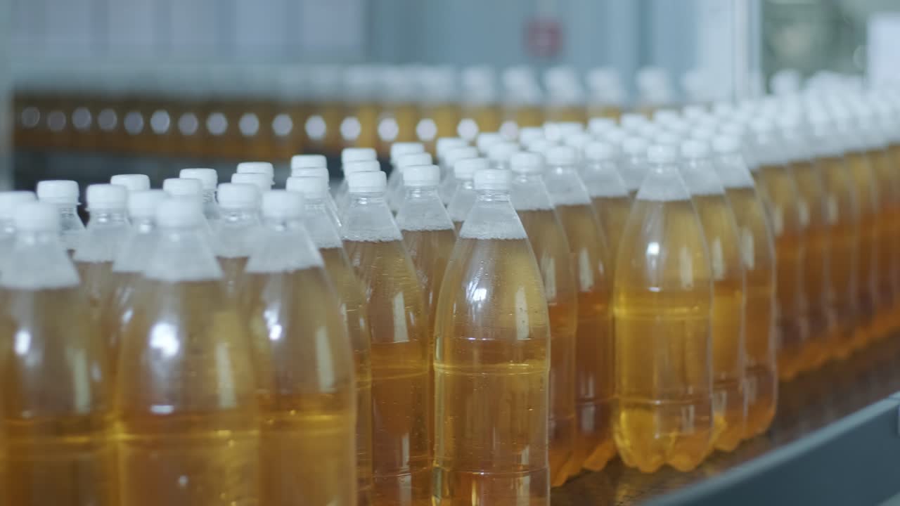Förderband mit Flaschen für Saft oder Wasser in einer modernen Getränkeanlage. Moderne Produktion von süßem Sprudelwasser