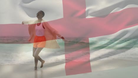 Animación-De-La-Bandera-De-Inglaterra-Sobre-Una-Feliz-Mujer-Afroamericana-Jugando-En-El-Agua-En-La-Playa.