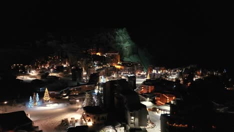 winter ski resort village and hotels lit-up at night, aerial view