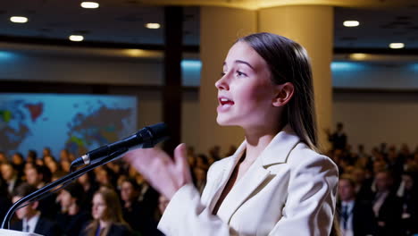 a young woman gives a speech at a conference with an audience