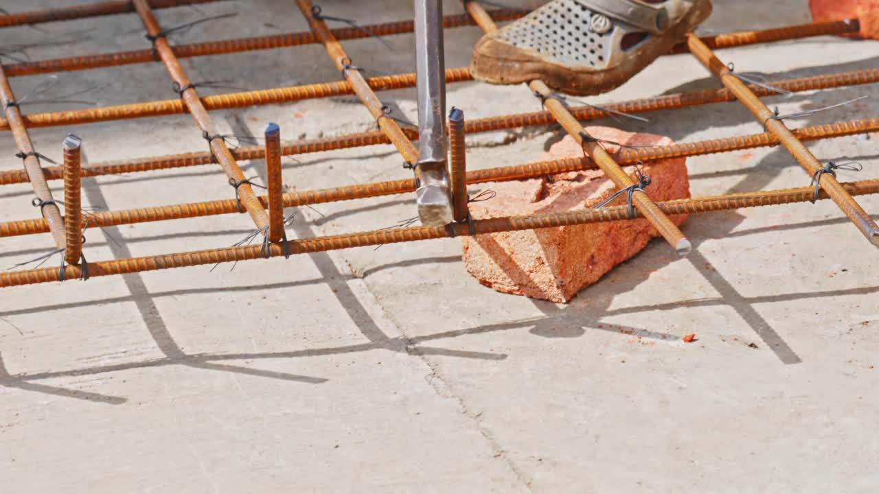 Person bending steel rods with bending lever for footing mat at construction site. day time, stable shot, 4k