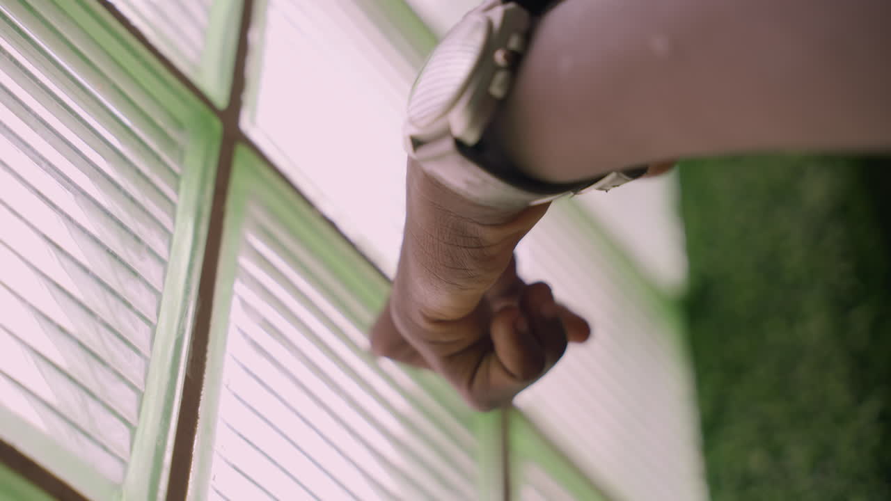 Closeup black hand on frosted glass, wristwatch visible, gentle press along patterned glass blocks, soft green background, warm afternoon light, intimate date mood, subtle longing and tender