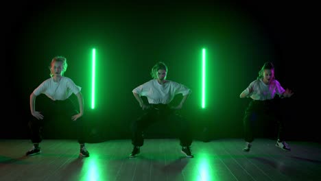 teenage girls performing hip hop dance routine under neon green lighting