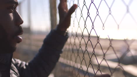 male prisoner looking through a wire fence