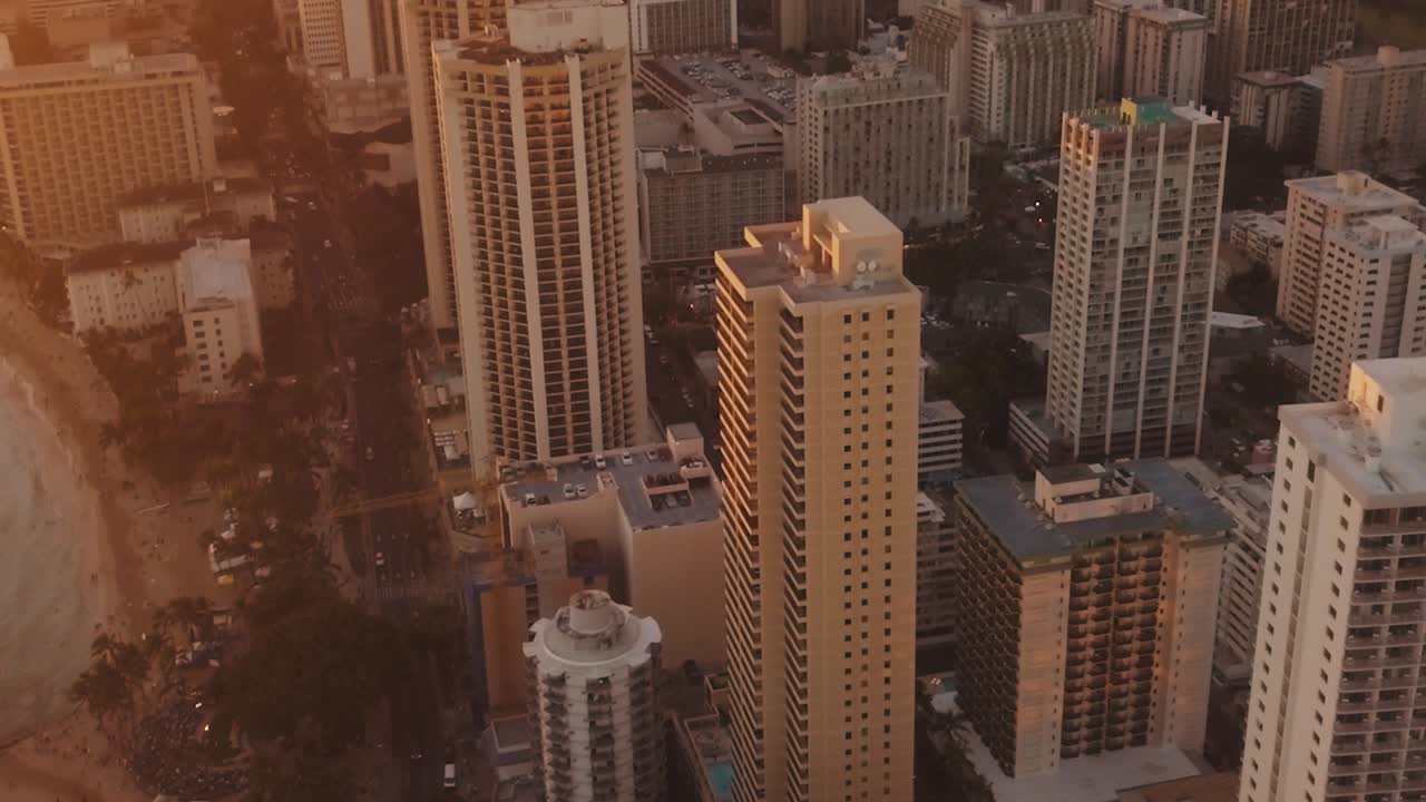 Panning aerial drone slowly flying over a colorful Honolulu Skyline while Sunset in Oahu, Hawaii with Waikiki Beach as a special point of interest