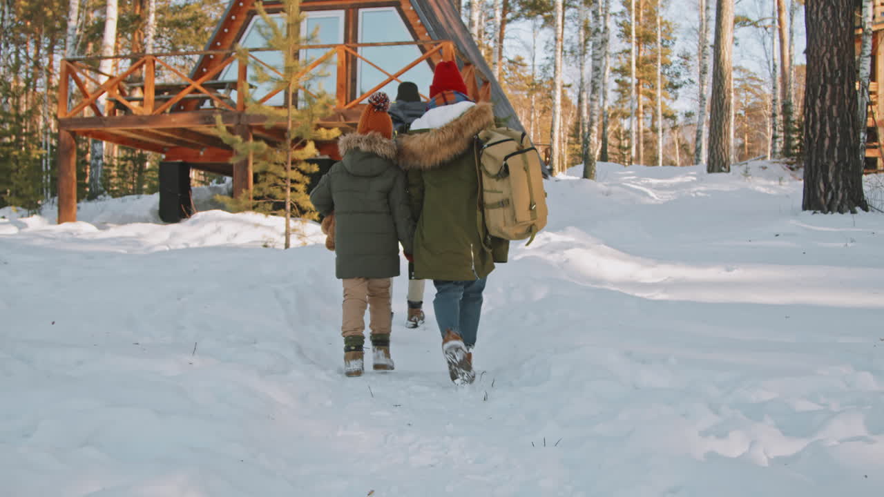 Familie på tre går mot hytte