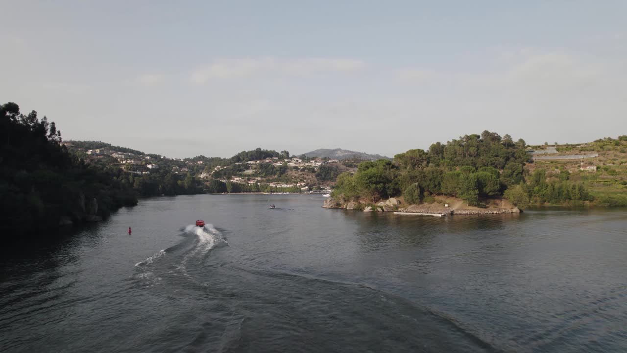 Tracciamento aereo di un motoscafo rosso che naviga sulle acque del fiume dell'Isola dell'Amore (Ilha dos Amores), Castelo de Paiva in Portogallo