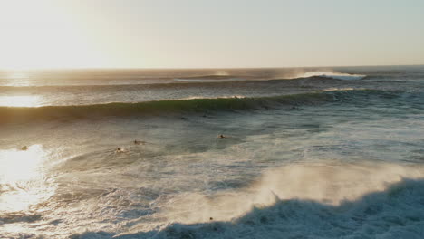 aerial of beatiful sunset on llandudno beach with surfers in the background in cape town