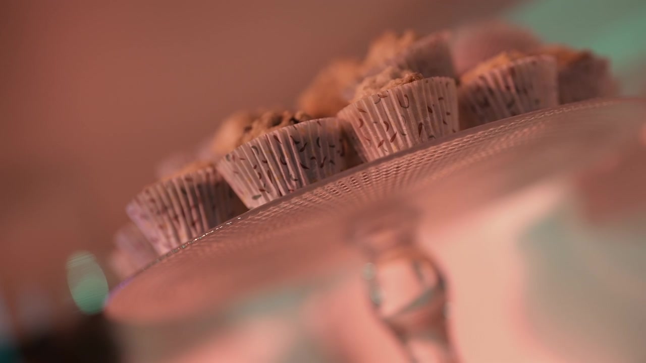 Cupcakes arranged on a glass stand, illuminated by warm ambient lighting. Perfect for event promotions or culinary presentations.