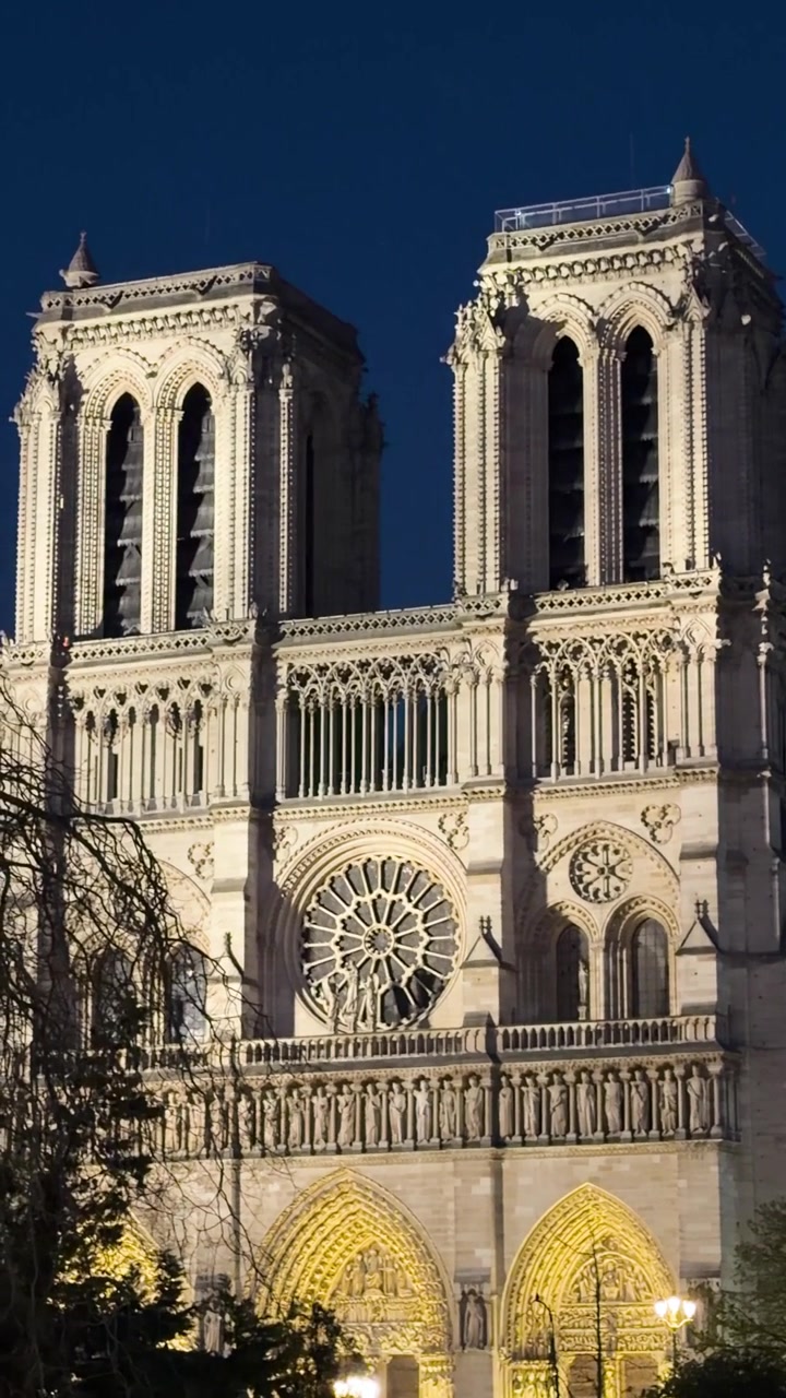 Koyu mavi gece gökyüzüne karşı, alacakaranlıkta Fransız başkentini aydınlatan Notre Dame de Paris Katedrali.