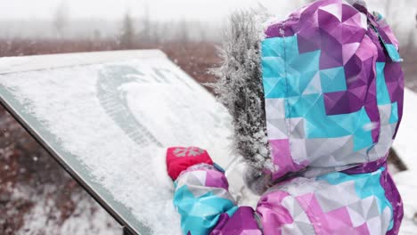 little-girl-wipes-snow-off-trail-sign-snowstorm-slomo-super-cute