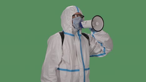 portrait of a man in a protective suit, safety glasses, gloves and a medical mask speaks into a megaphone warning people about the danger. green screen, chroma key. slow motion. close up