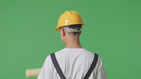 close up of back view asian man painter wearing safety helmet painting in the green screen background studio