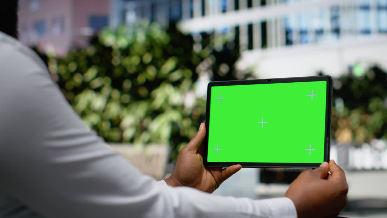 Horizontal green screen with black man sitting on a downtown bench