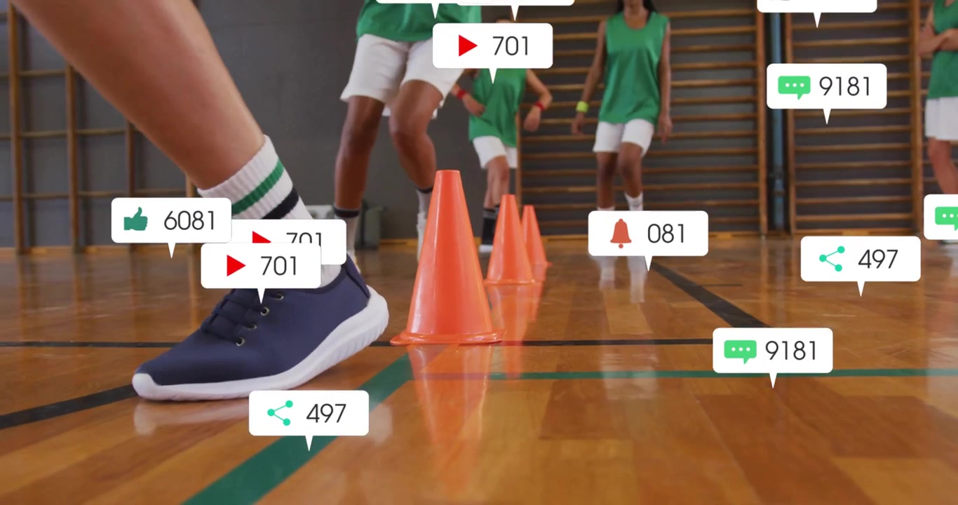 Sportlerinnen machen Agility-Hütchen-Übung in einer Sporthalle, wobei schwebende Social-Media-Symbole angezeigt werden.