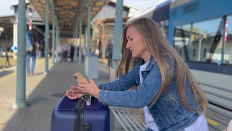 a female traveler sleeps on a suitcase while waiting for a train at a railway station. concept of tourism. vertical video