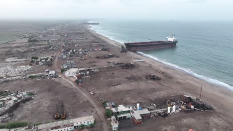 Vista-Aérea-Sobre-La-Playa-Con-Un-Gran-Barco-Varado-En-El-Patio-De-Desguace-De-Gadani