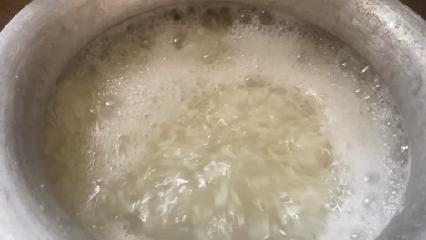 rice being cooked in pot with boiling water