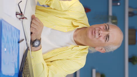 vertical video of home office worker old man looking annoyed at camera.