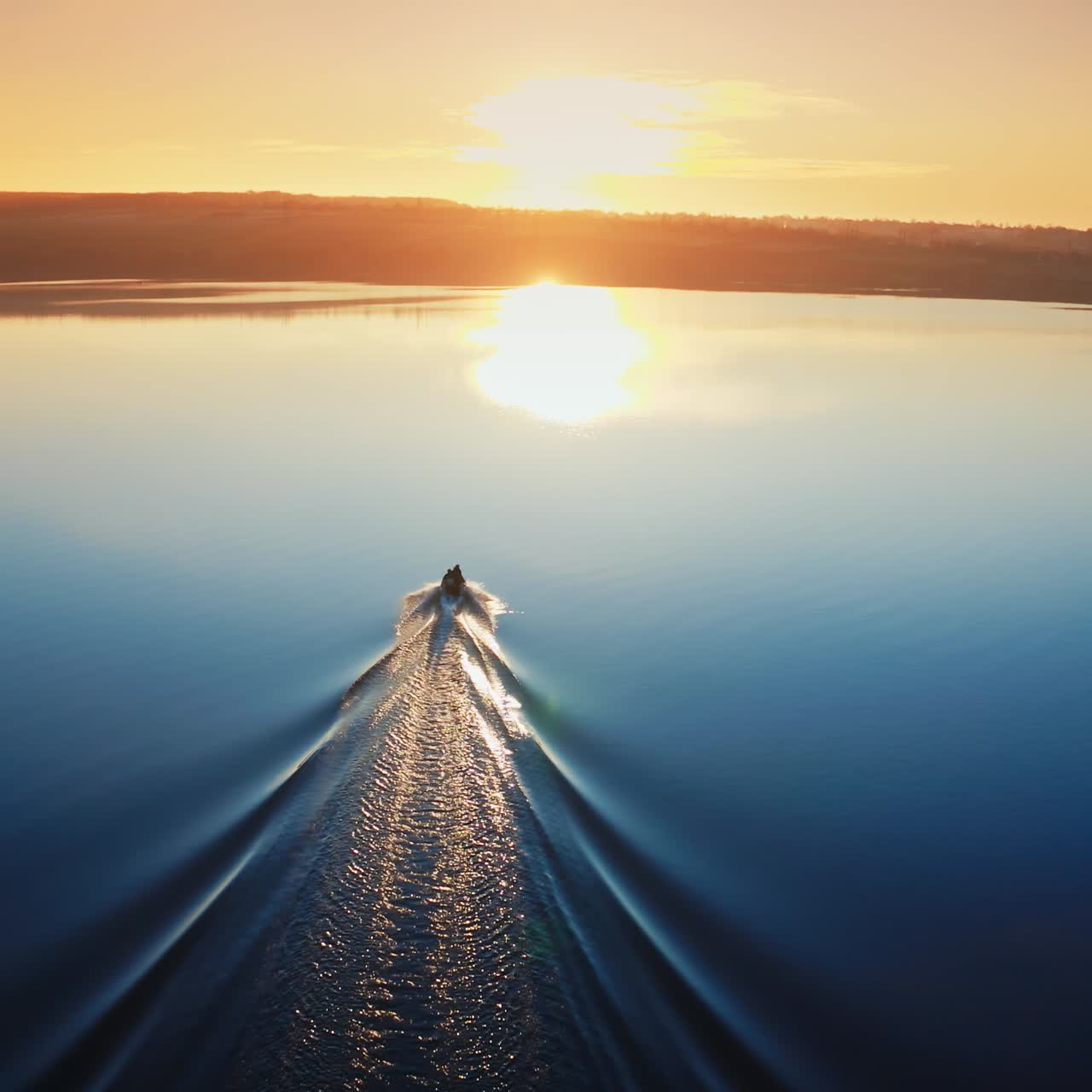 Motor boat floating on the river at sunset. Beautiful aerial view on the calm blue water in the evening. Boat moves along the river.