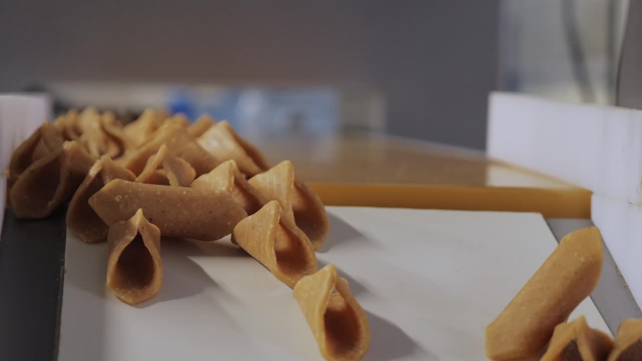 Primo piano di gusci di cioccolato a forma di cono e praline ripiene disposte su vassoi nella produzione di fabbrica