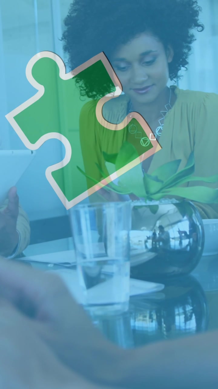 Animation of colourful puzzle pieces over business colleagues using tablets