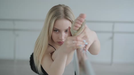 fit girl in black clothes performing contemporary. female dancer shows flowing motions, body and hands waves at white room. modern ballet dance choreography. young woman is moving smoothly