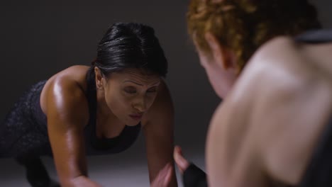 close up studio shot of two mature women wearing gym fitness clothing doing plank exercise together