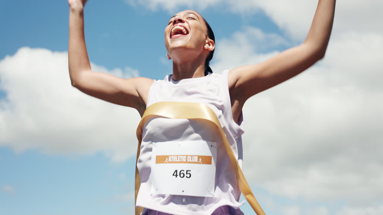 Excited Woman Runner Crosses Finish Line with Arms Raised in Victory