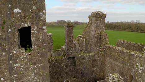 aerial pullback between bective abbey worn weathered moss covered walls on overcast day